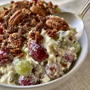 High-angle view of glossy creamy grape salad with a silver spoon lifting a portion.