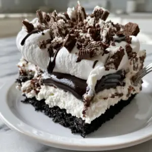 Close up 45-degree angle shot of an Oreo lasagna slice showing the glossy pudding and pillowy whipped cream layers. (no bake oreo dessert)