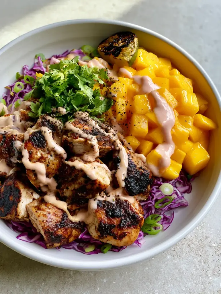 Jerk Chicken & Mango Slaw Bowls with Creamy Honey-Lime Drizzle 2 Close-up of seared jerk chicken chunks and bright golden mango cubes in a white bowl. (Jerk Chicken & Mango Slaw Bowls)