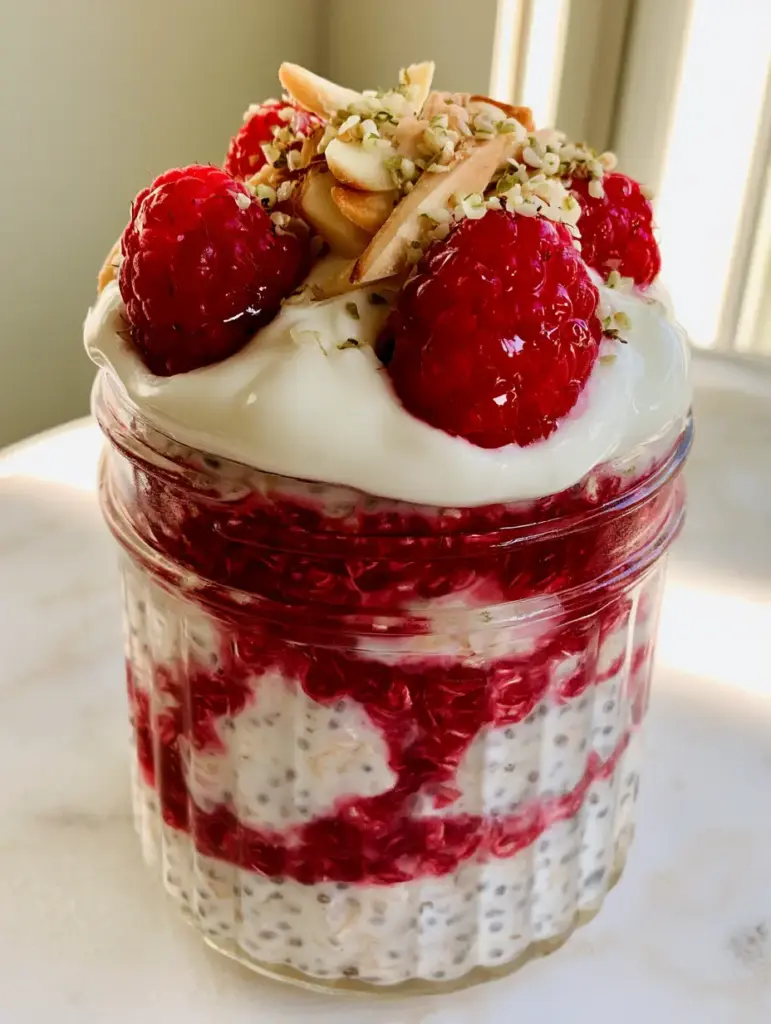 Raspberry Jam Overnight Oats: The Ultimate Creamy Breakfast Prep 1 Detailed shot of the toppings on raspberry jam overnight oats including fresh raspberries, hemp hearts, and toasted almonds.