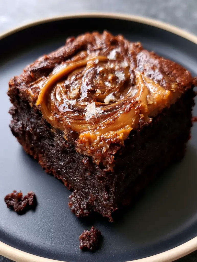 Overhead view of marbled peanut butter brownies on a dark matte plate with soft natural lighting.