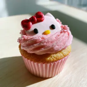 Moist golden-brown vanilla Hello Kitty cupcakes in pastel pink ribbed liners.