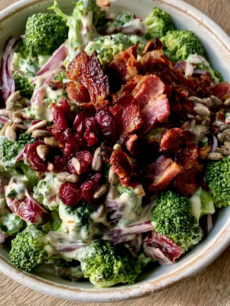 Close-up of jagged smoked bacon and ruby-red cranberries over emerald broccoli salad.
