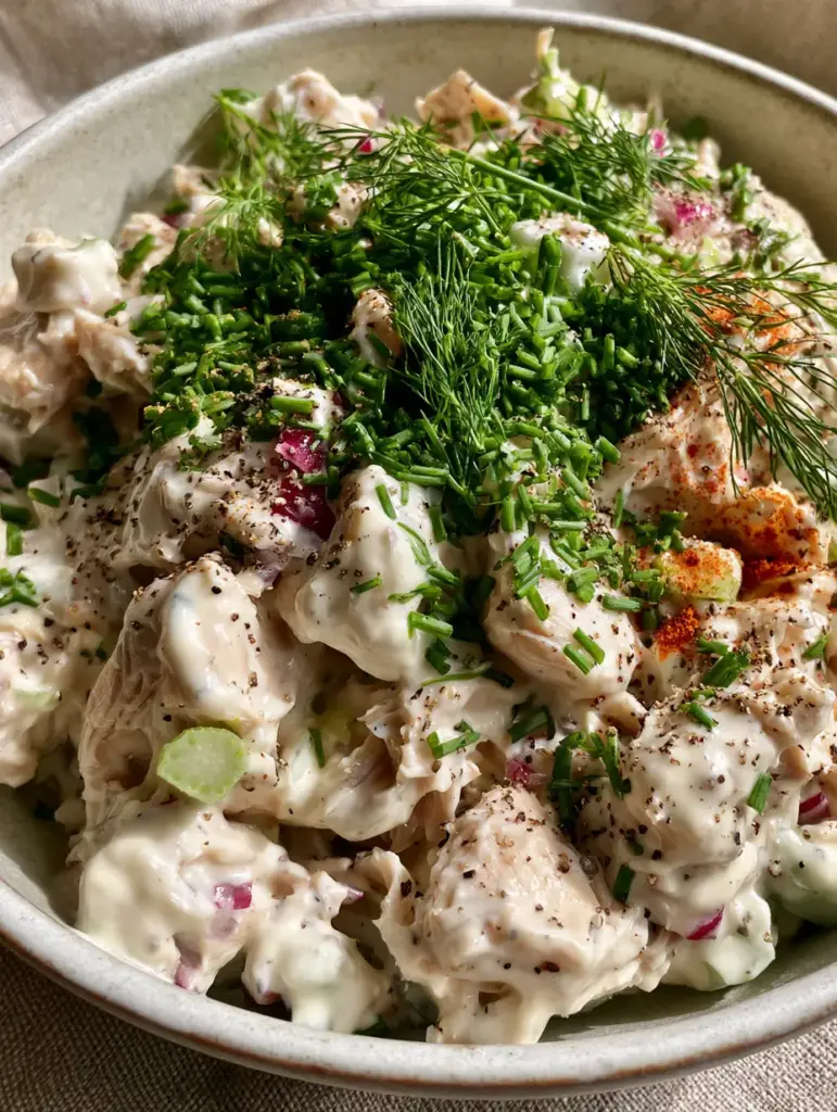 Cottage Cheese Chicken Salad: The Creamiest High-Protein Lunch 2 Extreme close-up of hand-shredded chicken coated in a smooth cottage cheese sauce with fresh herbs. (cottage cheese chicken salad)