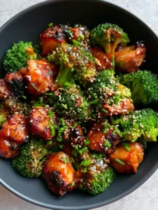 Close-up of caramelized Honey Sriracha Chicken chunks with charred edges and a thick translucent red glaze. (Honey Sriracha Chicken and Broccoli)